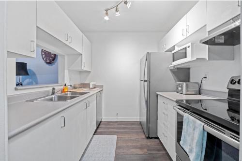 a kitchen with white cabinets and a stainless steel refrigerator at Cozy 1 Bedroom Downtown Central in Vancouver