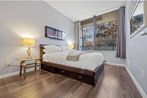 una camera da letto con un letto e una TV a parete di Cozy 1 Bedroom Downtown Central a Vancouver