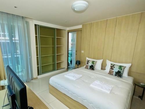 a bedroom with a large white bed and a television at Beachfront Patong Hillside Modern Apartment in Patong Beach