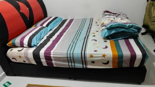 Una cama con un edredón y almohadas encima en Liza Homestay, en Bachok