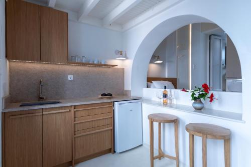 uma cozinha com armários de madeira, pia e banquetas em Andromeda Residence em Míconos