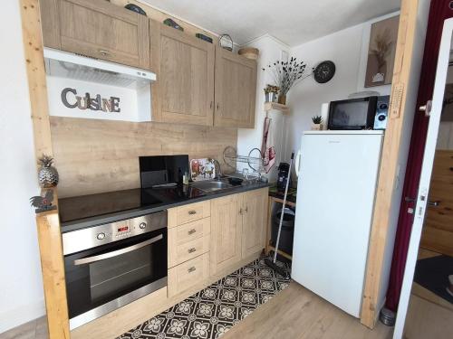 Una cocina con gabinetes de madera y un refrigerador blanco. en T2 cosy à Puyvalador - Ski & lac, en Puyvalador