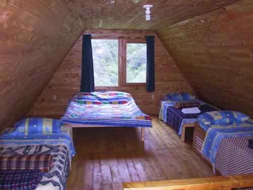 a room with two beds and a window in a log cabin at Quetzal Valley Cabins in San Gerardo de Dota