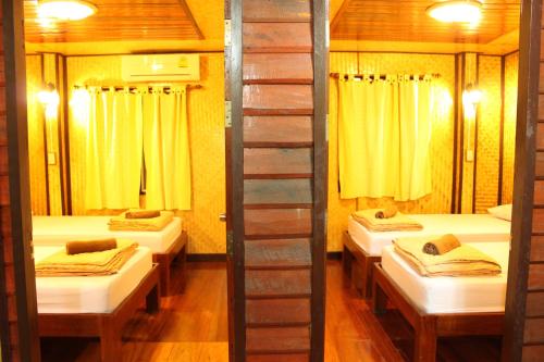 a room with three beds with yellow curtains at Baansuan Lychee Maeklong Resort Ampawa in Amphawa