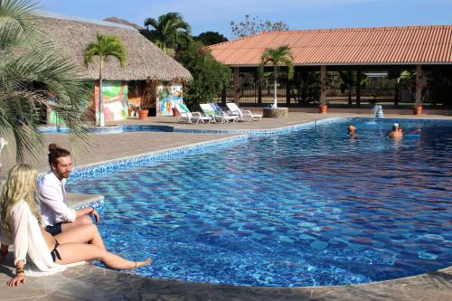 a man and woman sitting next to a swimming pool at Punta Chame Club and Resort One Bedroom Home in Pajonal