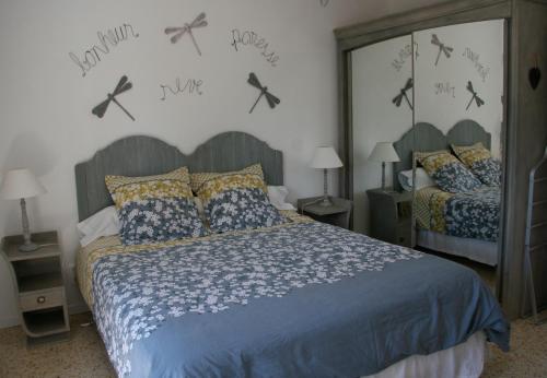 Mas de l'Estello في سان ريمي دو بروفنس: غرفة نوم بسرير مع لحاف ازرق وعبوس على الحائط