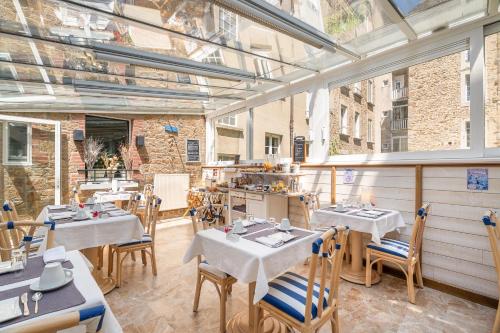 Un restaurante con mesas y sillas en una sala. en Hôtel Quic en Groigne, en Saint-Malo