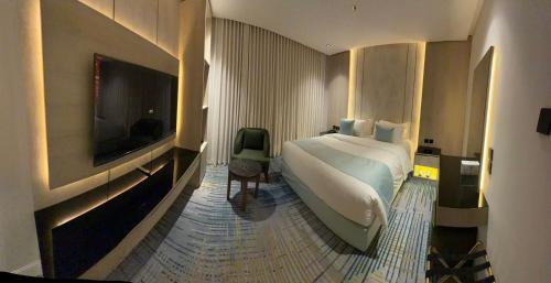 ein Schlafzimmer mit Bett und Flachbildfernseher in der Unterkunft Rose Garden Hotel فندق روز جاردن in Riad