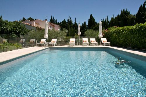 une piscine avec chaises et parasols dans l'établissement Mas de l'Estello, à Saint-Rémy-de-Provence