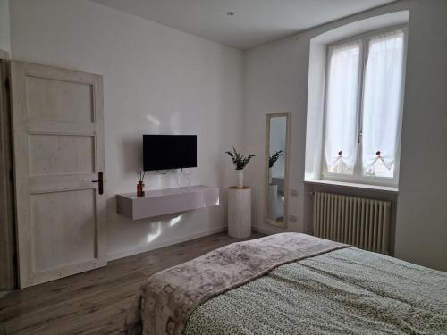 a white bedroom with a bed and a television at Trento Living in Trento