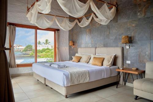 a bedroom with a large bed with a large window at Blu Galapagos Sustainable Waterfront Lodge in Puerto Ayora