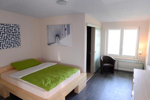 a bedroom with a bed with a green blanket on it at MOTEL BELP Bern Airport in Belp