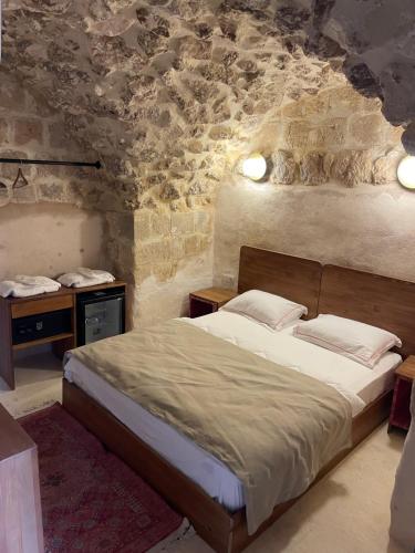 una camera da letto con un letto e un muro di pietra di Merani Hotel a Midyat