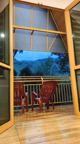 two chairs on a balcony with a view of the mountains at Cloud Peak in Vagamon