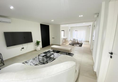 Una sala de estar con un sofá y un televisor en una pared. en The Estoria Lagos, en Ikeja
