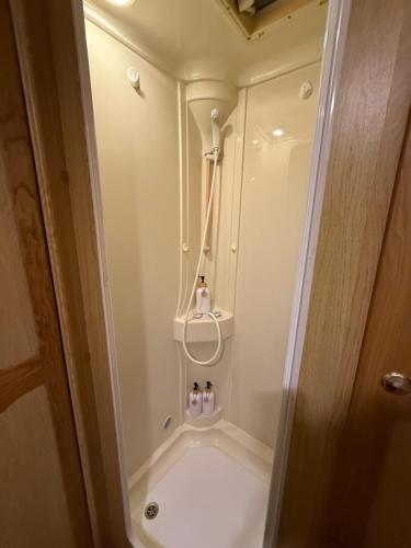 a small bathroom with a shower with two bottles in it at Samonrada Khao Yai Homestay in Pak Chong