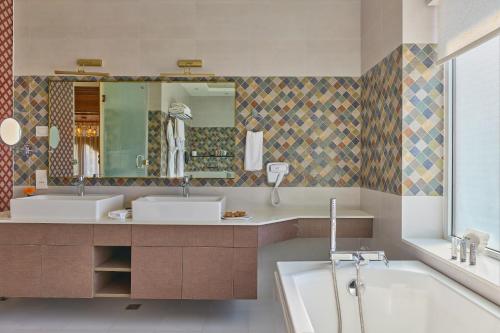 um banheiro com duas pias, uma banheira e um espelho em Soaltee Westend Resort Nagarkot em Nagarkot