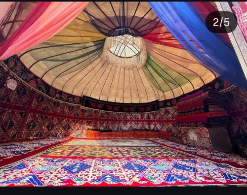 een kamer met een plafond en een kleurrijk tapijt op de vloer bij Maksyt Ata Hostel in Kalday