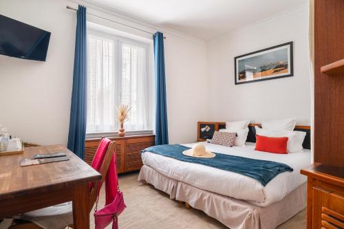 Un dormitorio con una cama, un escritorio y una mesa. en Hôtel Quic en Groigne, en Saint-Malo