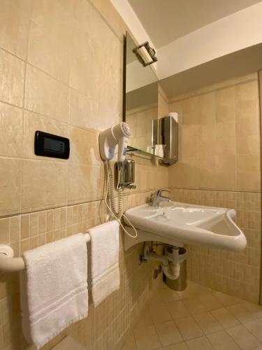 a bathroom with a sink and a mirror and towels at Garni La Genziana in Temù
