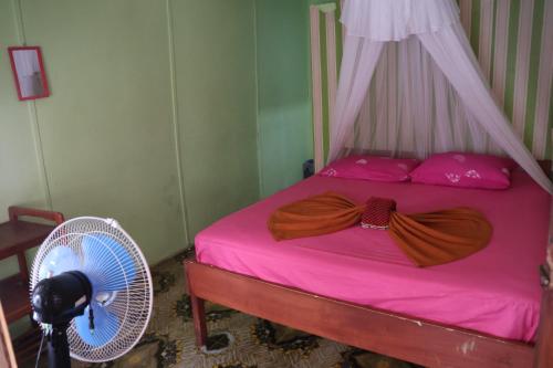 Fun Family Guest House n Jungle Tour في بوكيت لاوانج: غرفة نوم مع سرير وملاءات وردية ومروحة