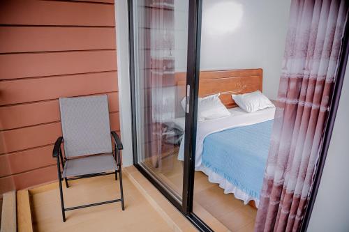 ein Schlafzimmer mit einem Bett, einem Stuhl und einem Fenster in der Unterkunft Agasaro House Kigali in Kigali