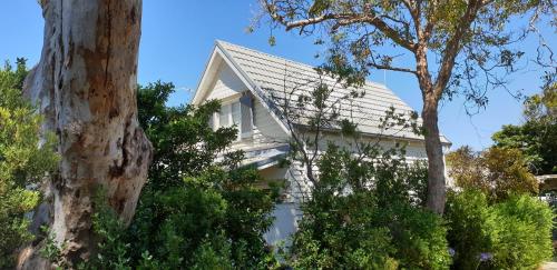 a white house with a pitched roof and trees at Kipsie Cottage - Point Lonsdale in Point Lonsdale