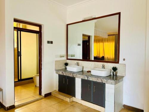 Un baño con dos lavabos y un espejo grande. en Nokras SilverOak Hotel, Embu, en Embu