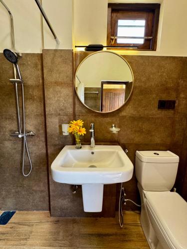 a bathroom with a sink and a toilet and a mirror at WILD PARADISE Apt in Unawatuna