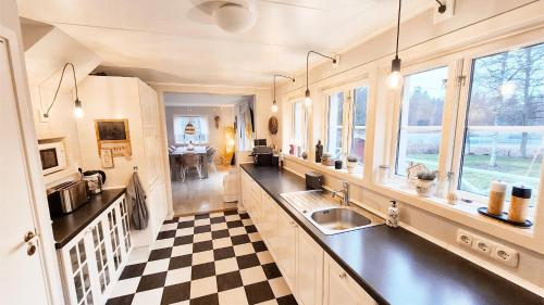 een keuken met een wastafel en een geruite vloer bij Brotorpet in Torsebo