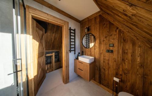 bagno con lavandino e parete in legno di WHITE BROOK Luxury Chalets a Witów