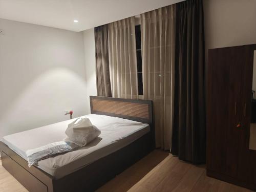 a bedroom with a bed with white sheets and a window at Palms Villa in Dharmpura