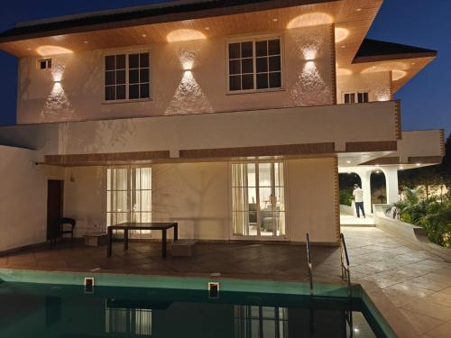 a house with a swimming pool in front of it at Palms Villa in Dharmpura
