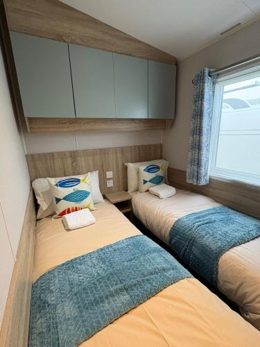 two beds in a small room with a window at Pine Tree Cove - your holiday retreat in Lytchett Minster