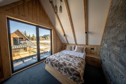 una camera da letto con un letto e una grande finestra di WHITE BROOK Luxury Chalets a Witów