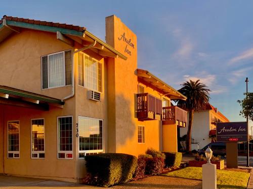 Un edificio amarillo con una palmera delante. en Avalon Inn Downtown Morro Bay, en Morro Bay