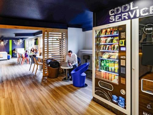 un restaurante con nevera y gente sentada en las mesas en Ibis budget Saint-Étienne stade, en Saint-Étienne
