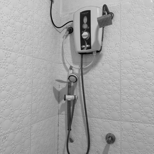 a shower with a hose attached to a wall at Eco Resort Kandy in Kandy