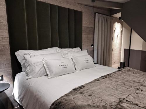 a bedroom with a large bed with white pillows at VHĀUS Apartment and Spa in Predazzo