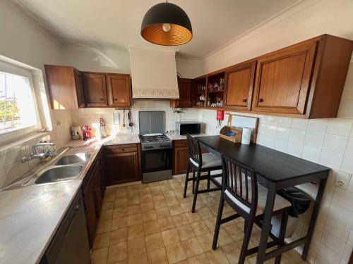 a kitchen with wooden cabinets and a black table with chairs at Casa Pausa Sesimbra Holiday Home in Sesimbra