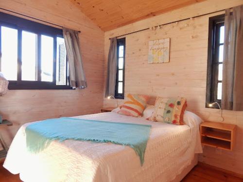 a bedroom with a bed and two windows at Ocean Paradise 1 in Punta Del Diablo