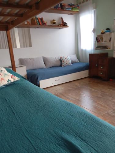 a bedroom with a blue bed and a couch at Casa para disfrutar en Necochea 5 personas in Necochea
