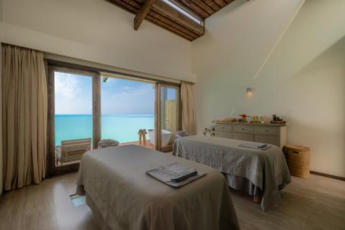 a bedroom with two beds and a large window at Nala Maldives by Jawakara in Lhaviyani Atoll