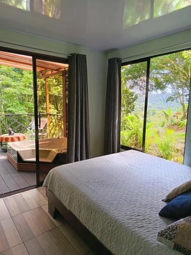 a bedroom with a bed and a large window at Breezes Ecolodge in San Ramón