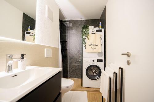 a bathroom with a washing machine and a sink at Urban Comfort, Zurich Airport - By River Glatt in Glattbrugg