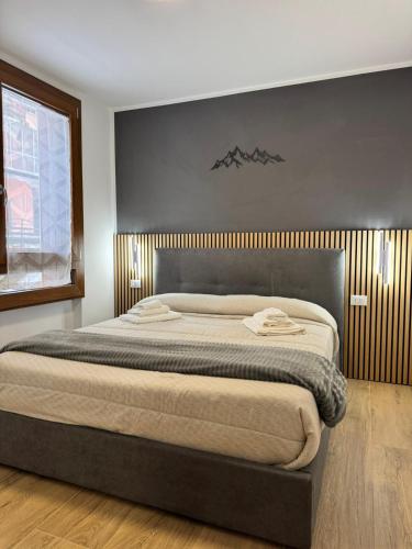 a bedroom with a large bed with a wooden headboard at Cima Bianca Suite in Passo del Tonale