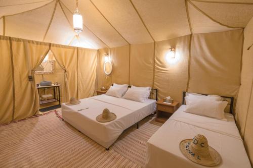 a bedroom with two beds in a tent at Erg Chebbi Dunes Desert Camp in Merzouga