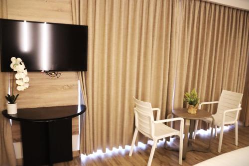Una habitación con una mesa y sillas y un televisor. en ALENA HOTEL, en Áqaba