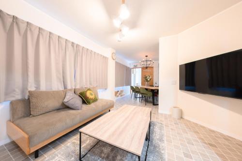 a living room with a couch and a flat screen tv at 一棟貸切りNagoya west2 in Nishi-biwajima