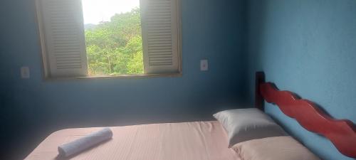 a bedroom with a bed with a window in it at De la rosa y el canto de los pájaros in Paraty
